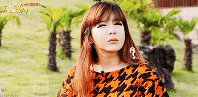 A Girl With A Question Mark On Her Forehead Is Standing In A Field With Palm Trees . GIF