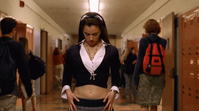 A Girl With A Red Backpack Is Standing In A Hallway With Other People GIF