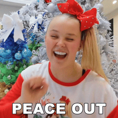 A Girl With A Red Bow In Her Hair Is Laughing In Front Of A Christmas Tree With The Words Peace Out Below Her GIF