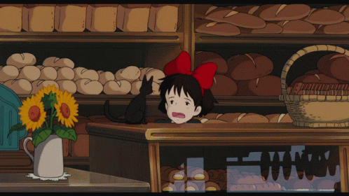 A Girl With A Red Bow On Her Head Stands In Front Of A Bakery GIF