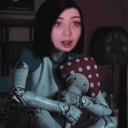A Girl With A Robotic Arm Is Holding A Stuffed Animal GIF