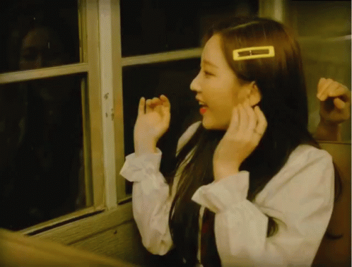 A Girl With A Yellow Hair Clip On Her Head Looks Out A Window GIF