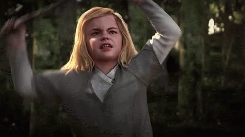 A Girl With Blonde Hair And A White Shirt Is Holding Her Head In The Air GIF