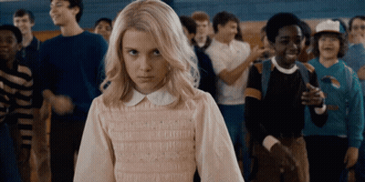A Girl With Blonde Hair Is Standing In Front Of A Crowd Of People GIF