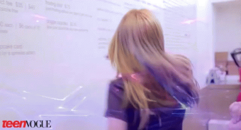 A Girl With Blonde Hair Is Standing In Front Of A White Board That Says Teenvogue GIF