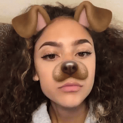 A Girl With Curly Hair Is Wearing A Dog Face Mask . GIF
