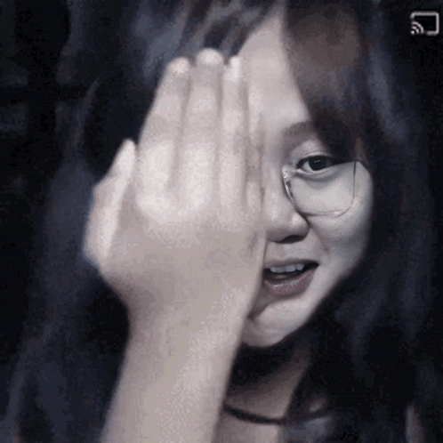 A Girl With Glasses Is Covering Her Face With Her Hand . GIF