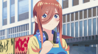 A Girl With Headphones Around Her Neck Is Standing In Front Of A Building GIF