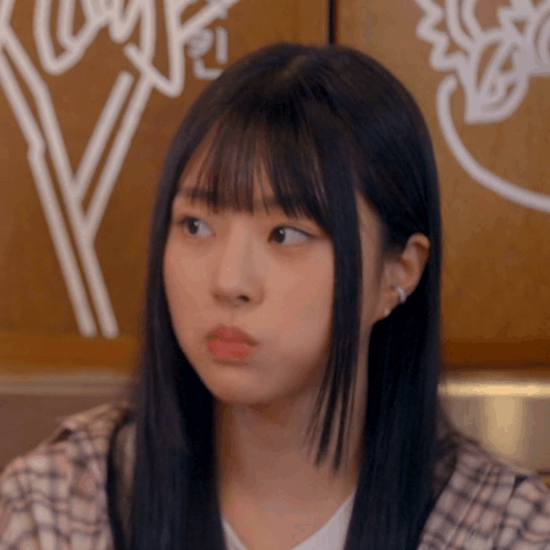 A Girl With Long Black Hair And Bangs Looks To The Side GIF