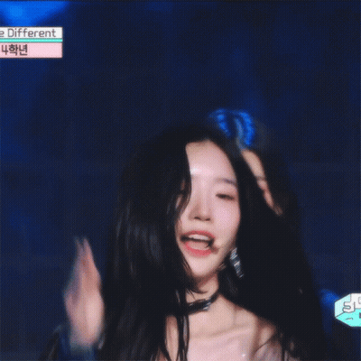 A Girl With Long Black Hair Is Smiling In Front Of A Sign That Says ' E Different ' GIF