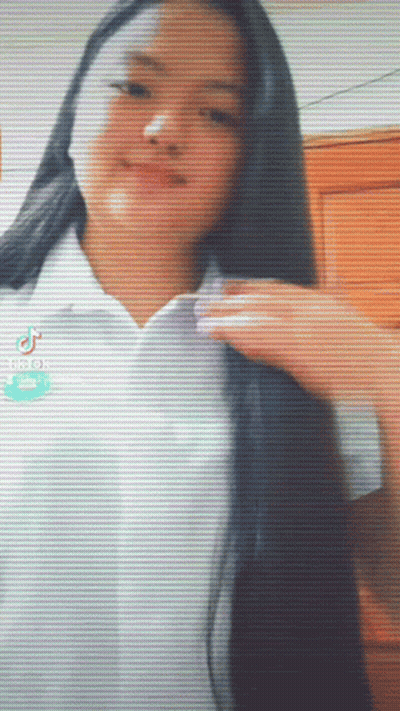 A Girl With Long Black Hair Is Wearing A White Shirt With Tiktok Written On The Bottom GIF