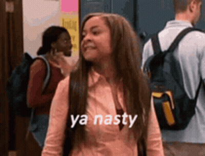 A Girl With Long Hair And A Backpack Is Standing In A Hallway With Other People . GIF
