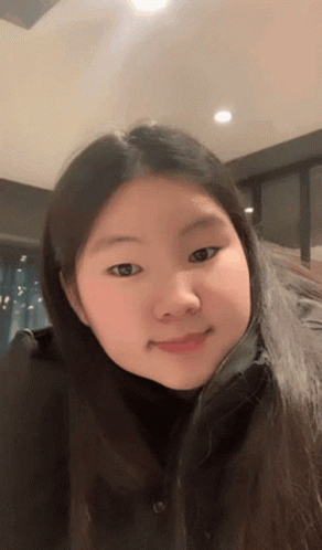 A Girl With Long Hair And A Black Shirt Is Smiling For The Camera GIF