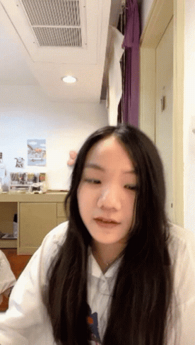 A Girl With Long Hair Is Sitting In A Room With A Ceiling Fan GIF