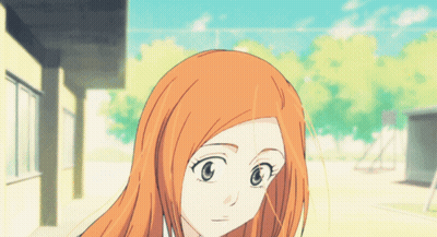 A Girl With Long Orange Hair And Blue Eyes Is Standing In Front Of A Building GIF