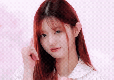 A Girl With Long Red Hair Is Looking At The Camera And Pointing At Her Hair GIF