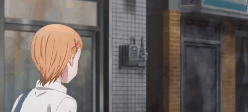 A Girl With Orange Hair Is Standing In Front Of A Store And Looking Out The Window . GIF