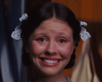 A Girl With Pigtails And A Bow In Her Hair Smiles For The Camera GIF