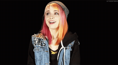 A Girl With Pink And Orange Hair Wearing A Denim Jacket And A Beanie GIF