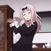 A Girl With Pink Hair And A Bow On Her Head Is Dancing In Front Of A Cabinet . GIF