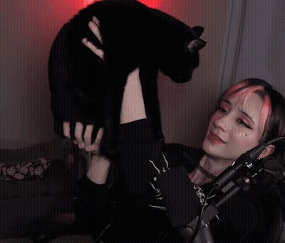 A Girl With Pink Hair Holds A Black Cat In Her Arms GIF