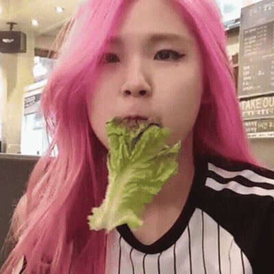A Girl With Pink Hair Is Eating Lettuce In A Restaurant GIF