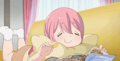 A Girl With Pink Hair Is Laying On A Couch Eating Chips And Reading A Magazine GIF