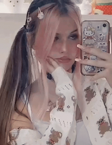 A Girl With Pink Hair Is Taking A Selfie In Front Of A Mirror . GIF