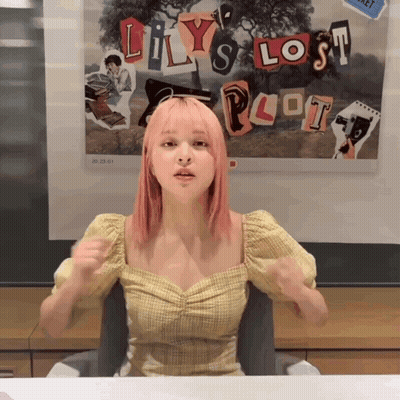 A Girl With Pink Hair Sitting In Front Of A Poster That Says Lily 'S Lost Plot GIF