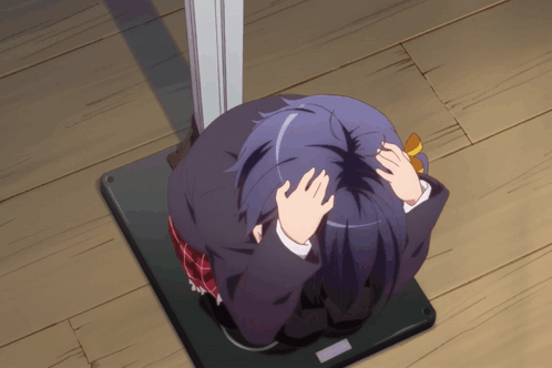 A Girl With Purple Hair Is Sitting On A Wooden Floor Covering Her Face With Her Hands GIF