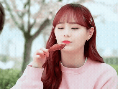 A Girl With Red Hair Eating A Piece Of Meat GIF