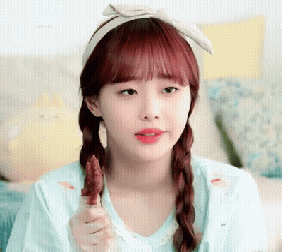 A Girl With Red Hair Is Wearing A Headband And Eating A Piece Of Meat GIF