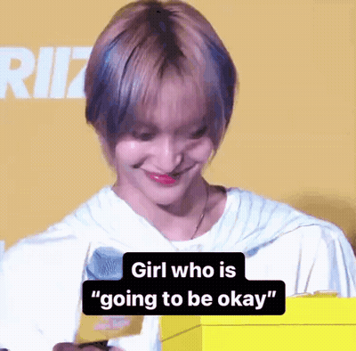 A Girl With Short Hair Is Smiling And Holding A Yellow Box With The Words `` Girl Who Is Going To Be Okay '' On It . GIF