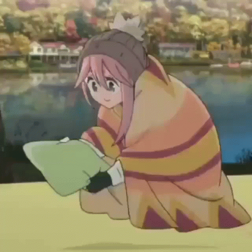 A Girl Wrapped In A Blanket Is Sitting On A Table Reading A Book . GIF