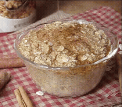 A Glass Bowl Filled With Oatmeal And Cinnamon Sticks On A Checkered Table Cloth . GIF