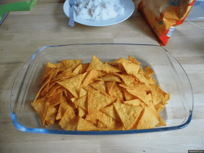 A Glass Dish Filled With Tortilla Chips Next To A Bag Of Tortilla Chips GIF