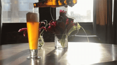 A Glass Of Beer Is Being Poured From A Bottle GIF