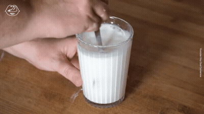 A Glass Of Milk Is Stirred With A Spoon GIF