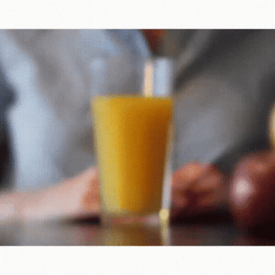 A Glass Of Orange Juice Sitting On A Table GIF