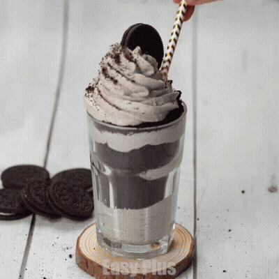 A Glass Of Oreo Milkshake With Whipped Cream And A Straw On Top GIF