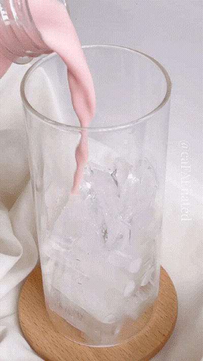 A Glass Of Pink Liquid Is Being Poured Into Ice GIF