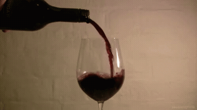 A Glass Of Red Wine Is Being Poured From A Bottle That Says " Avignon " On It GIF