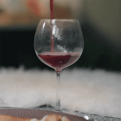 A Glass Of Red Wine Is Being Poured Into The Glass GIF