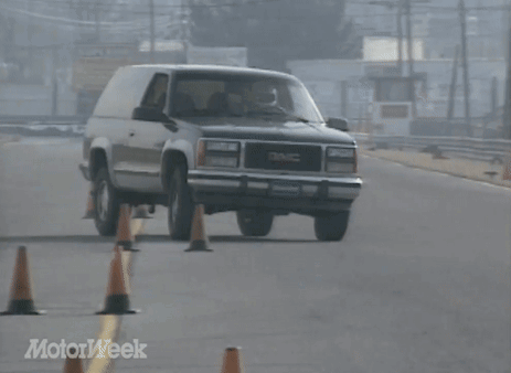 A Gmc Suv Is Driving Down A Road Surrounded By Orange Cones GIF