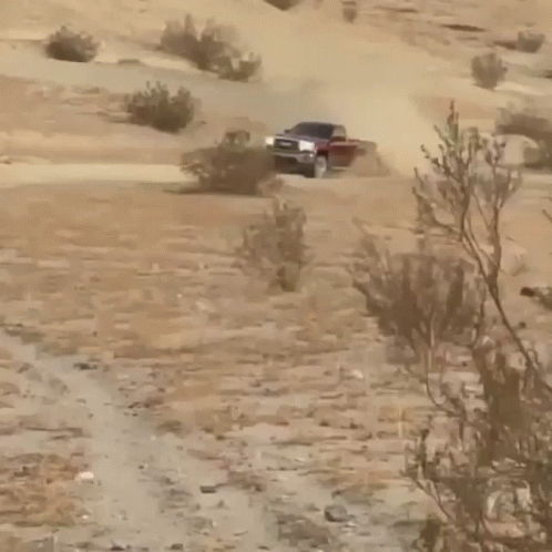 A Gmc Truck Driving Down A Dirt Road GIF