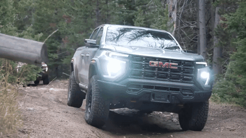 A Gmc Truck Driving Down A Dirt Road GIF