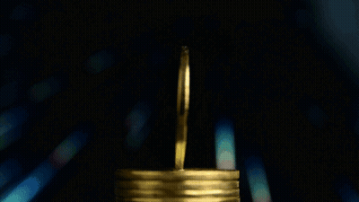 A Gold Coin With The Letter B On It Is On A Stack Of Gold Confetti GIF