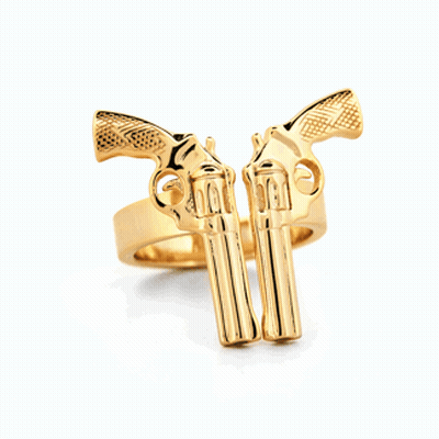 A Gold Ring With Two Guns On It On A White Surface GIF