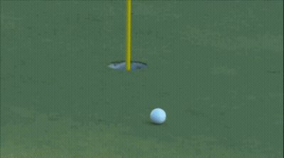 A Golf Ball Is Going Into A Hole On A Golf Course GIF