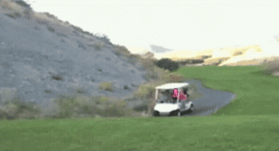 A Golf Cart Is Driving Down A Path On A Golf Course With A Flag That Says U.s.a. GIF